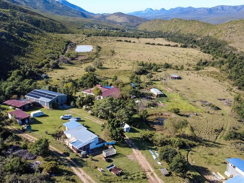 Aerial view of a rural farm property featuring multiple outbuildings, solar installations, a small dam, and expansive surrounding landscape.