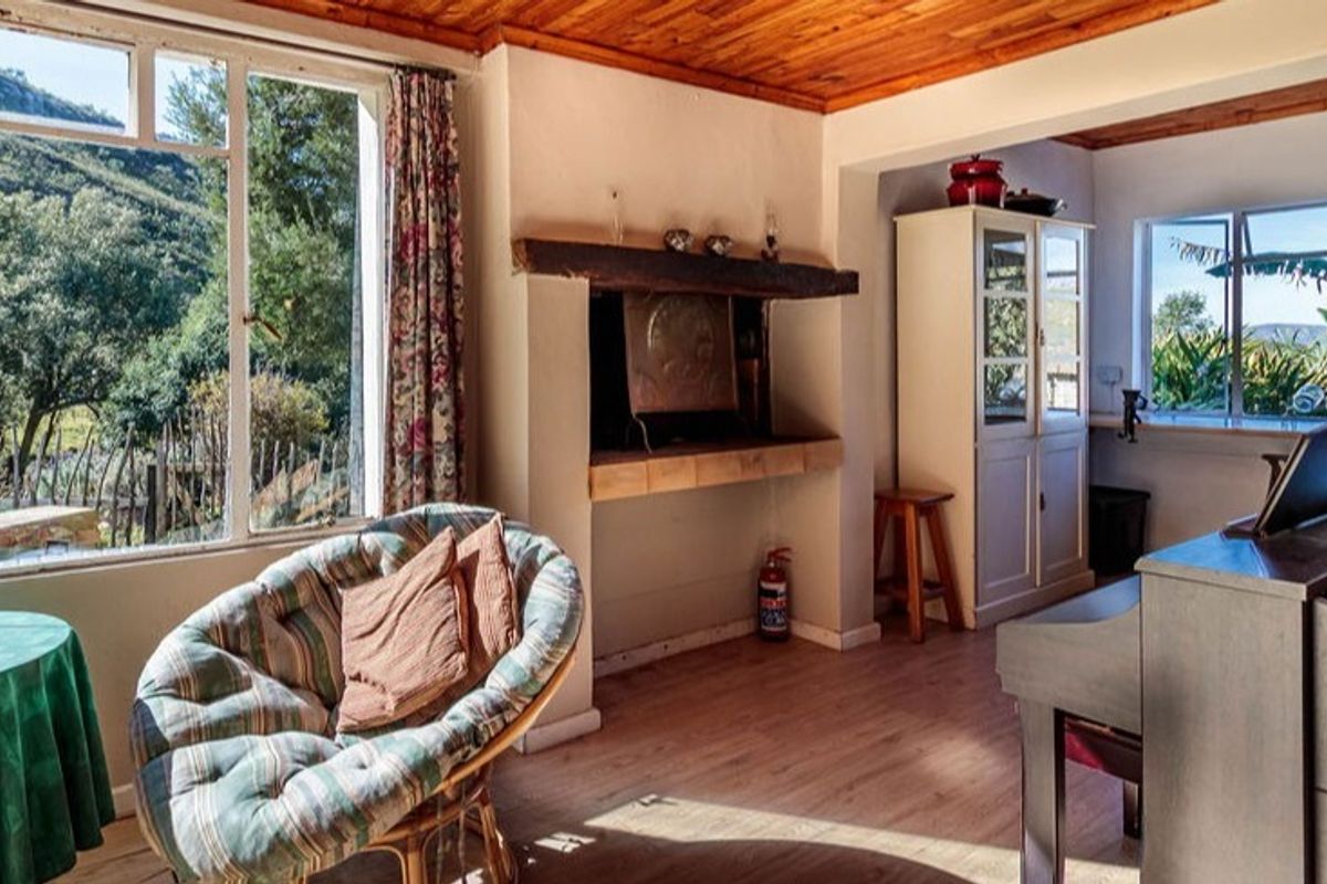 A living room featuring a timber ceiling, laminate flooring, and a built-in fireplace with a timber mantelpiece, offering views of the surrounding landscape.