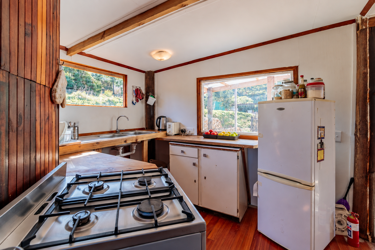 Rustic kitchen featuring timber wall paneling, wooden countertops, a gas cooktop, and stainless steel sink with views of the surrounding farm landscape.