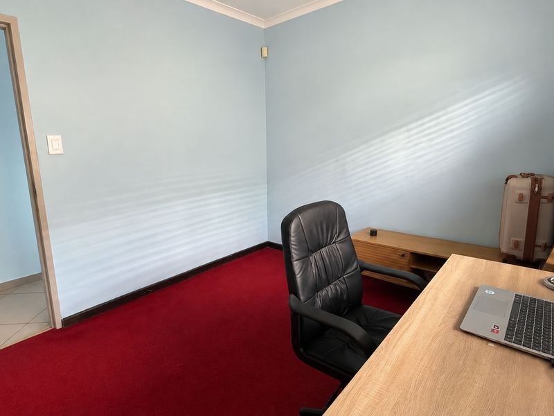 A functional office space featuring red carpeting and light blue walls, providing a simple and practical area for work or study.