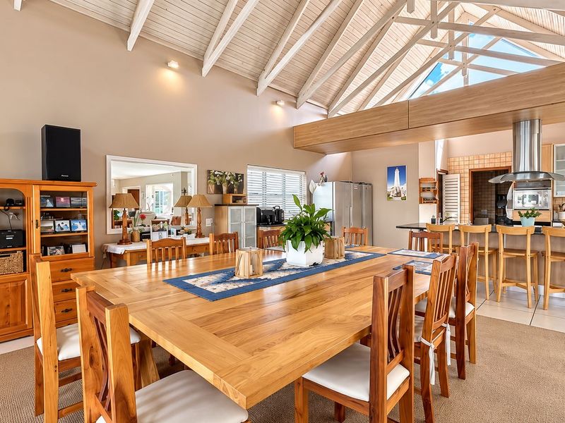 Spacious open-plan living and dining area featuring a dramatic vaulted timber ceiling with exposed trusses, a modern kitchen island, and abundant natural light.