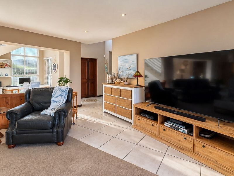 Spacious open-plan living area featuring a mix of tiled and carpeted flooring, recessed lighting, and an integrated staircase leading to the upper level.