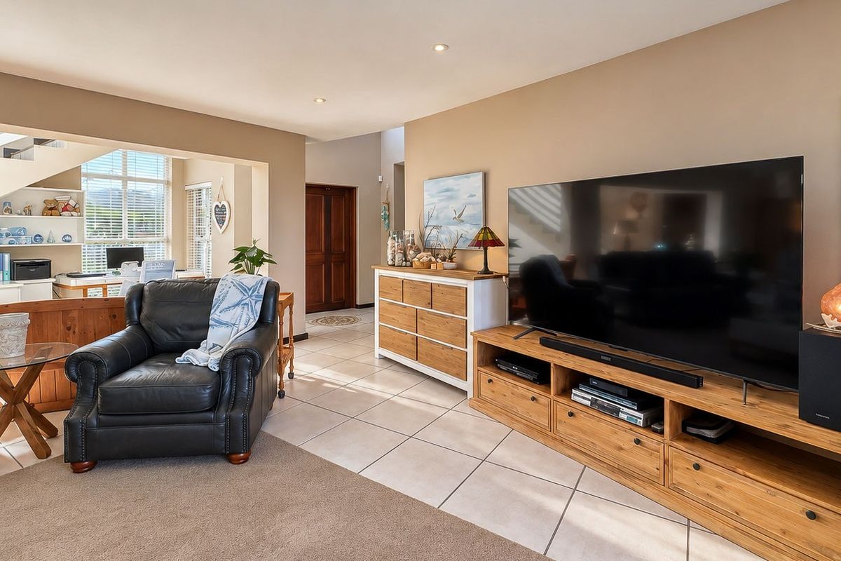 Spacious open-plan living area featuring a mix of tiled and carpeted flooring, recessed lighting, and an integrated staircase leading to the upper level.