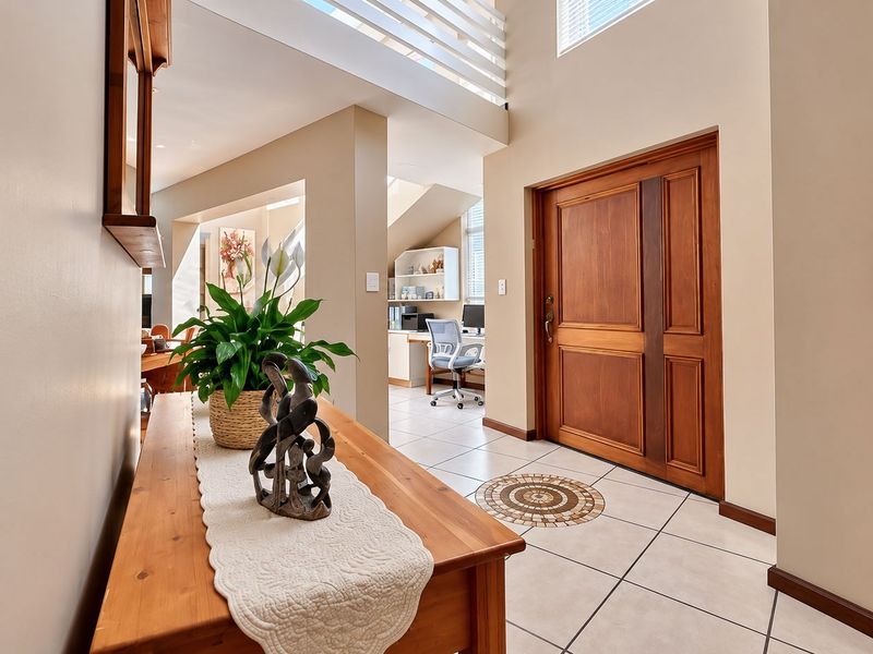 Welcoming entrance hall featuring tiled flooring, a solid wood front door, and an open-plan view towards a built-in home office area.