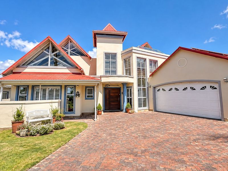 A well-maintained front elevation featuring a distinctive architectural design with red metal roofing, a paved driveway, and an integrated double garage.