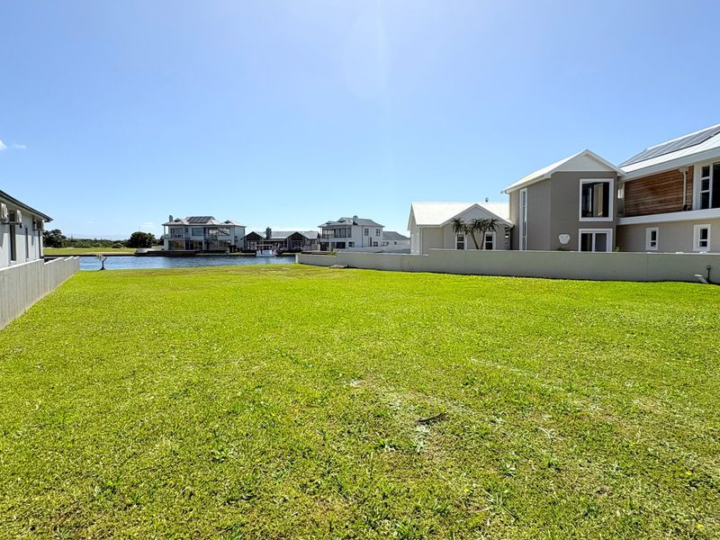 A spacious, well-maintained vacant residential plot featuring a level lawn, boundary walls, and direct access to the waterfront.