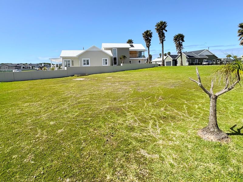 A spacious, well-maintained vacant residential plot featuring a manicured lawn, boundary wall, and established landscaping in a quiet neighborhood setting.