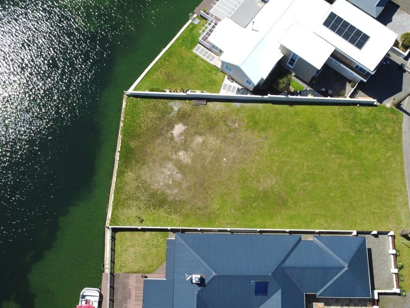 Aerial view of a vacant residential waterfront plot, featuring clear boundaries and direct access to the canal.