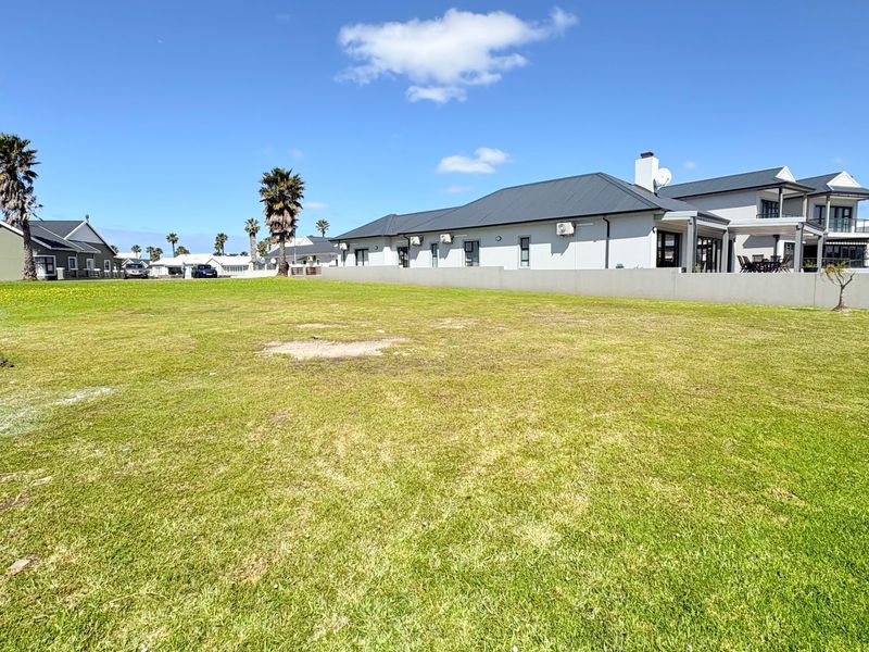 A spacious, level residential vacant plot featuring a well-maintained lawn and secure boundary walls, situated in a developed neighborhood.