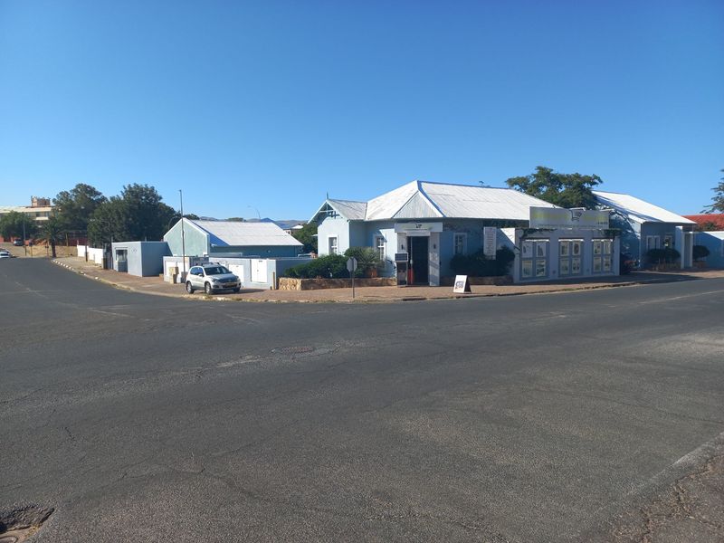 Corner office property featuring a light blue facade, corrugated metal roofing, and prominent street-level signage with convenient access.