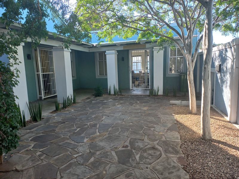 A well-maintained rear courtyard featuring stone paving, mature trees, and secure access points to the office building.