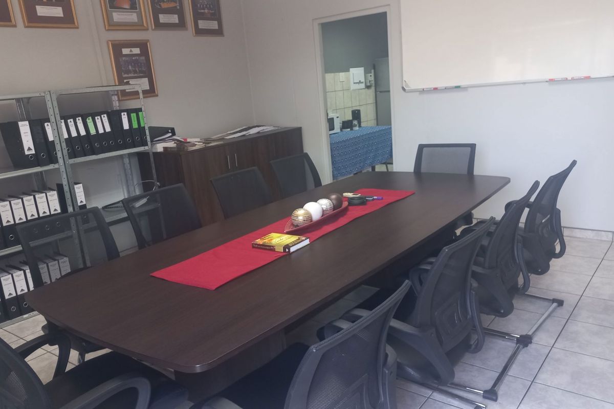 A functional office meeting room featuring tiled flooring and a wall-mounted whiteboard, providing a professional space for collaborative work.
