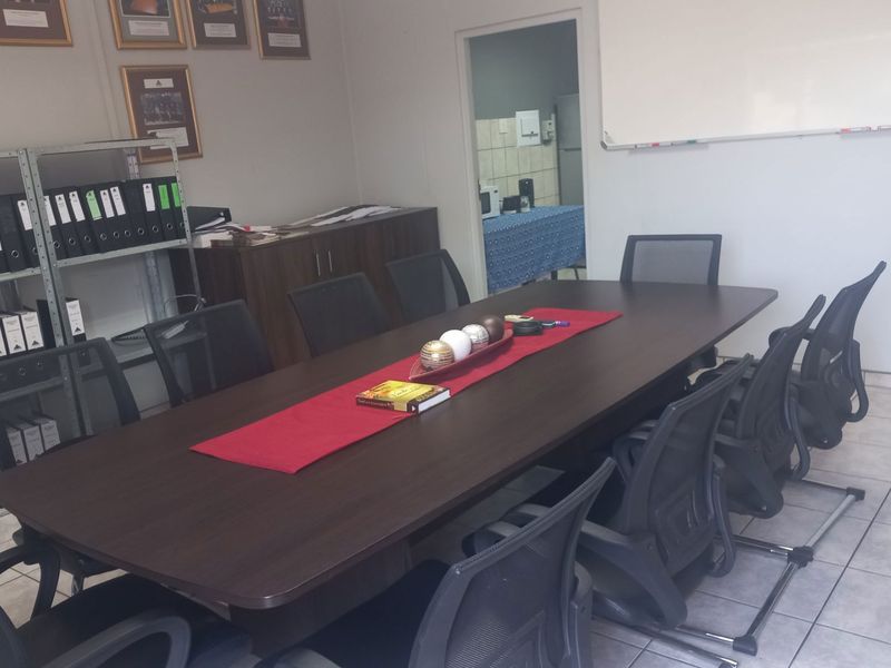 A functional office meeting room featuring tiled flooring and a wall-mounted whiteboard, providing a professional space for collaborative work.