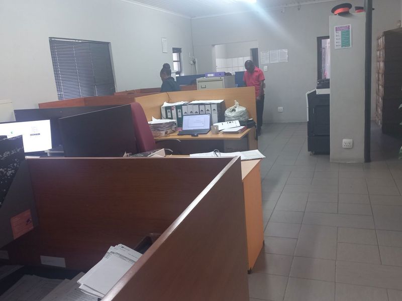 A functional office space featuring tiled flooring and venetian blinds, providing a practical work environment.