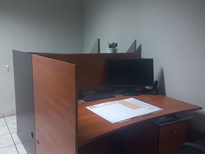 A functional office workspace featuring tiled flooring and a built-in desk partition, providing a practical environment for professional tasks.