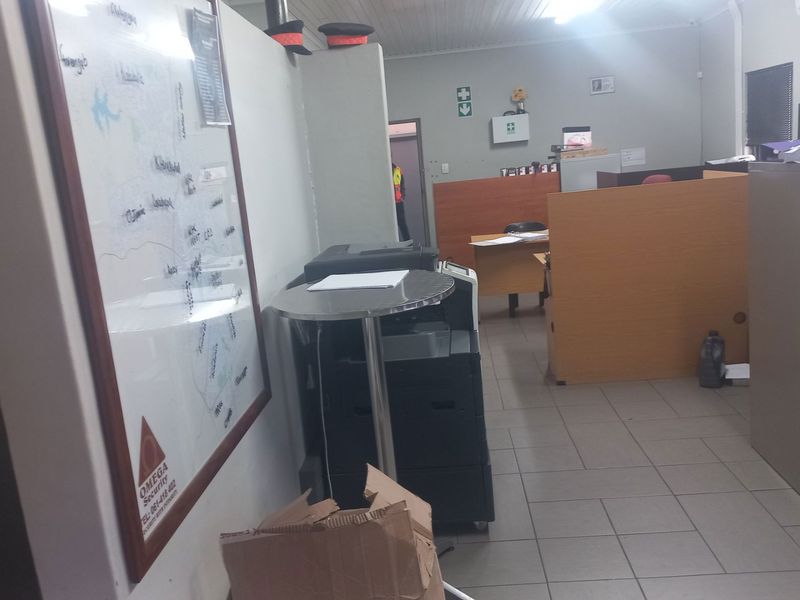 A functional office space featuring tiled flooring, partition walls, and an integrated air conditioning unit, suitable for a professional work environment.