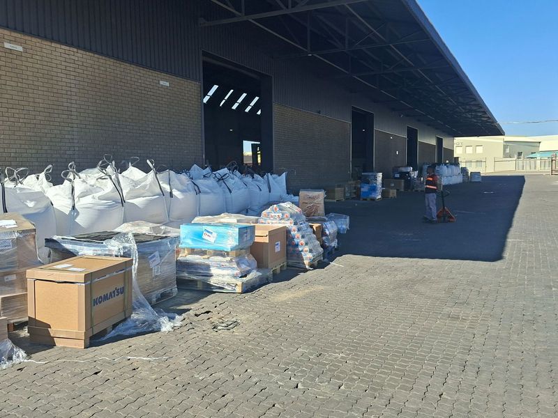 Industrial loading yard featuring a brick facade, metal roof canopy, and paved surface, suitable for logistics and warehouse operations.