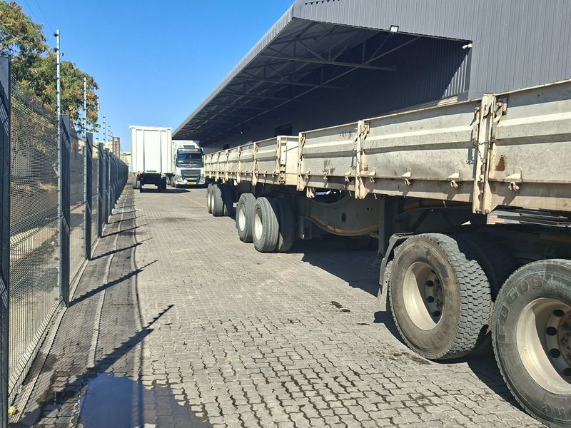 Industrial exterior yard featuring a paved loading area, covered loading bay, and secure perimeter fencing.