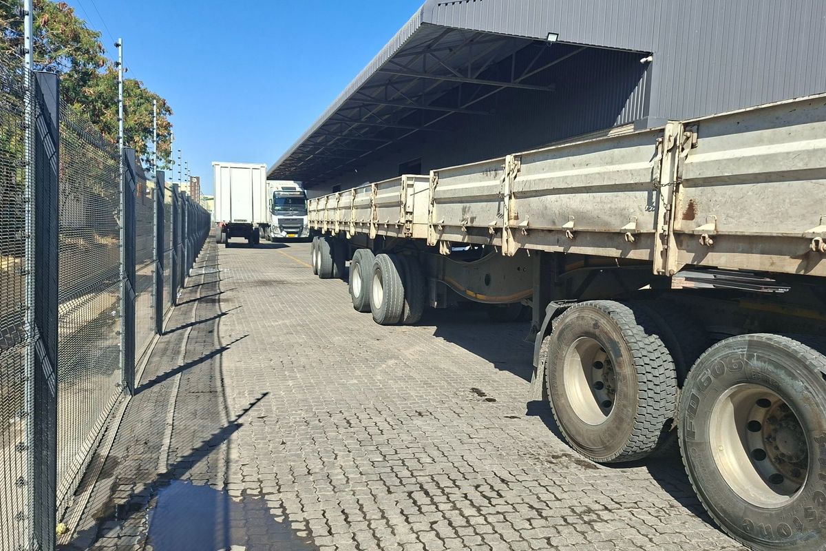 Industrial exterior yard featuring a paved loading area, covered loading bay, and secure perimeter fencing.