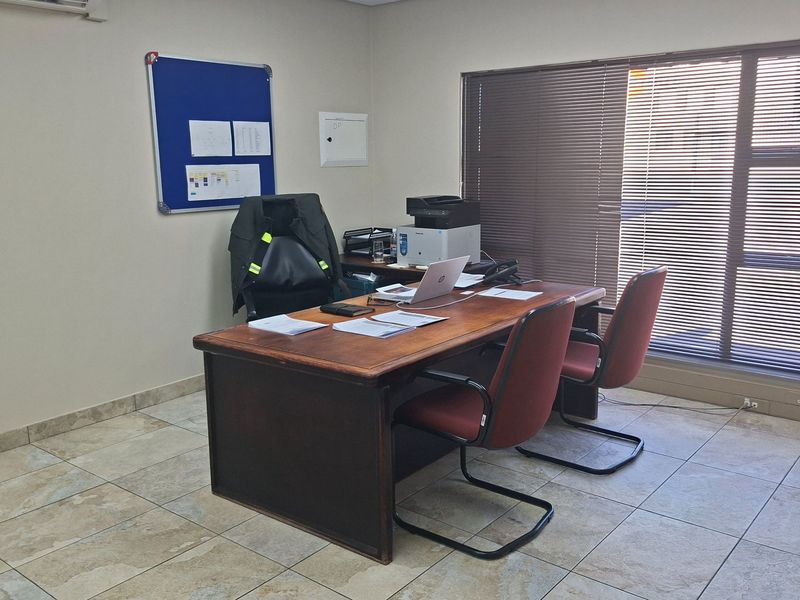 A functional office space featuring tiled flooring, venetian blinds, and an integrated air conditioning unit, suitable for professional use.