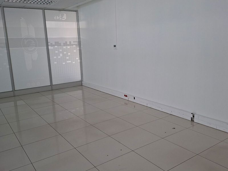 A vacant office space featuring polished tile flooring, glass partition walls, and integrated electrical trunking, suitable for a professional workspace.