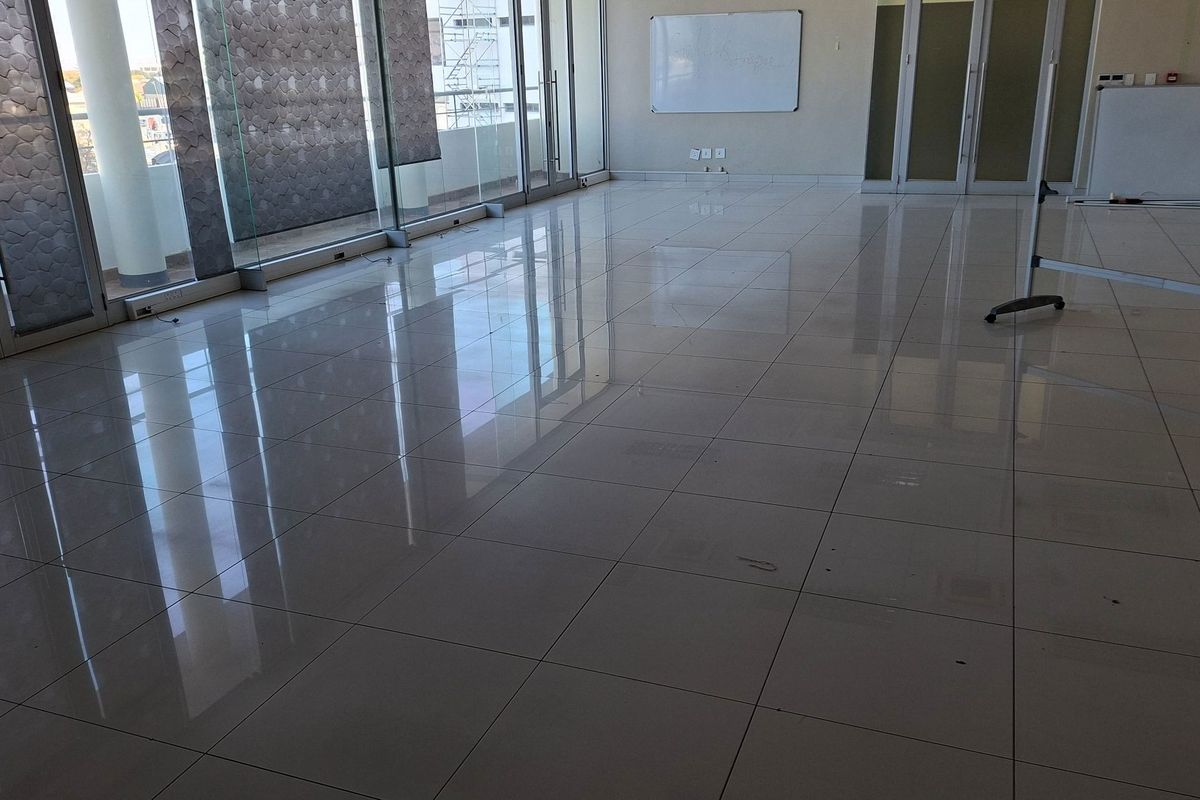 Spacious, modern office area featuring polished porcelain floor tiles, large glass sliding doors for natural light, and glass partition walls.