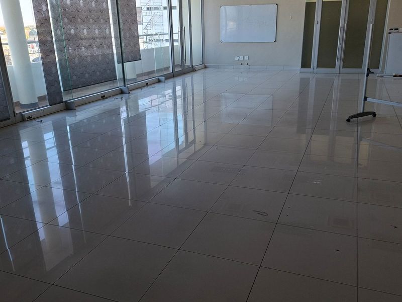 Spacious, modern office area featuring polished porcelain floor tiles, large glass sliding doors for natural light, and glass partition walls.