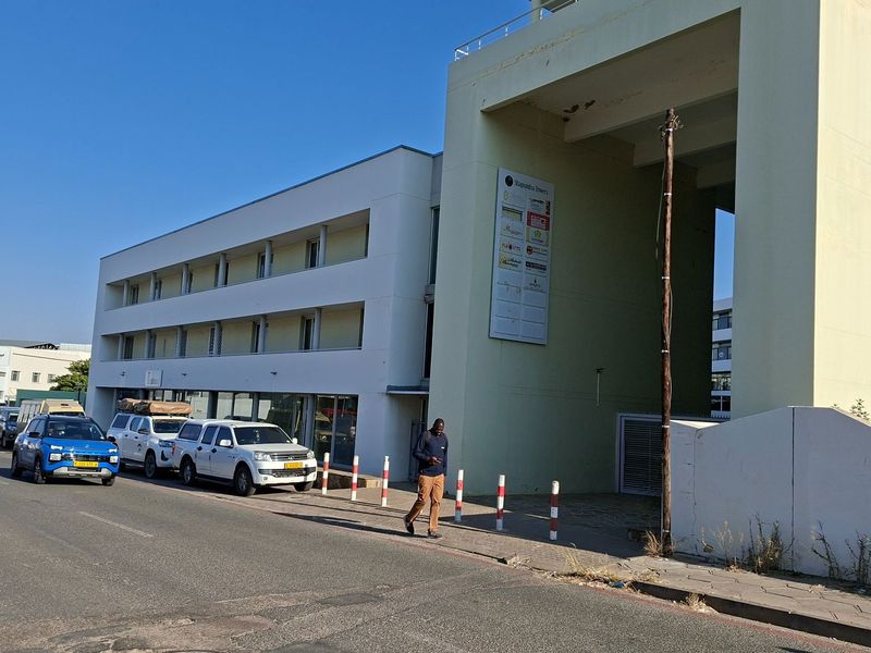 Exterior view of a multi-story office building featuring a paved sidewalk and prominent building signage.