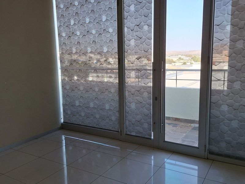 Empty office space featuring polished tile flooring and large glass sliding doors providing access to an outdoor balcony area.