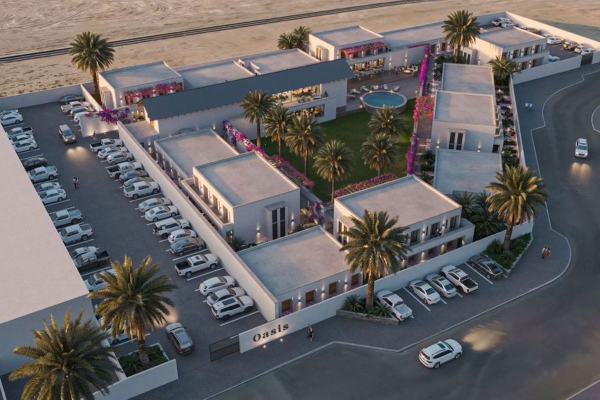 Aerial view of the Oasis apartment complex, featuring landscaped courtyards, a central pool area, and dedicated parking facilities.