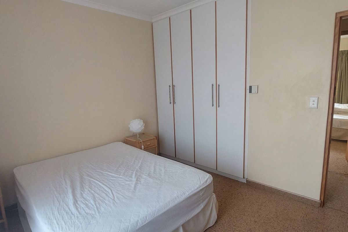 A bedroom featuring built-in wardrobes with white doors and neutral wall finishes, providing functional storage space.