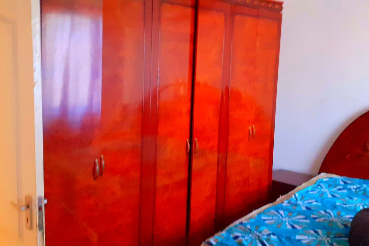 A bedroom featuring a large, polished wood-finish built-in wardrobe providing ample storage space.