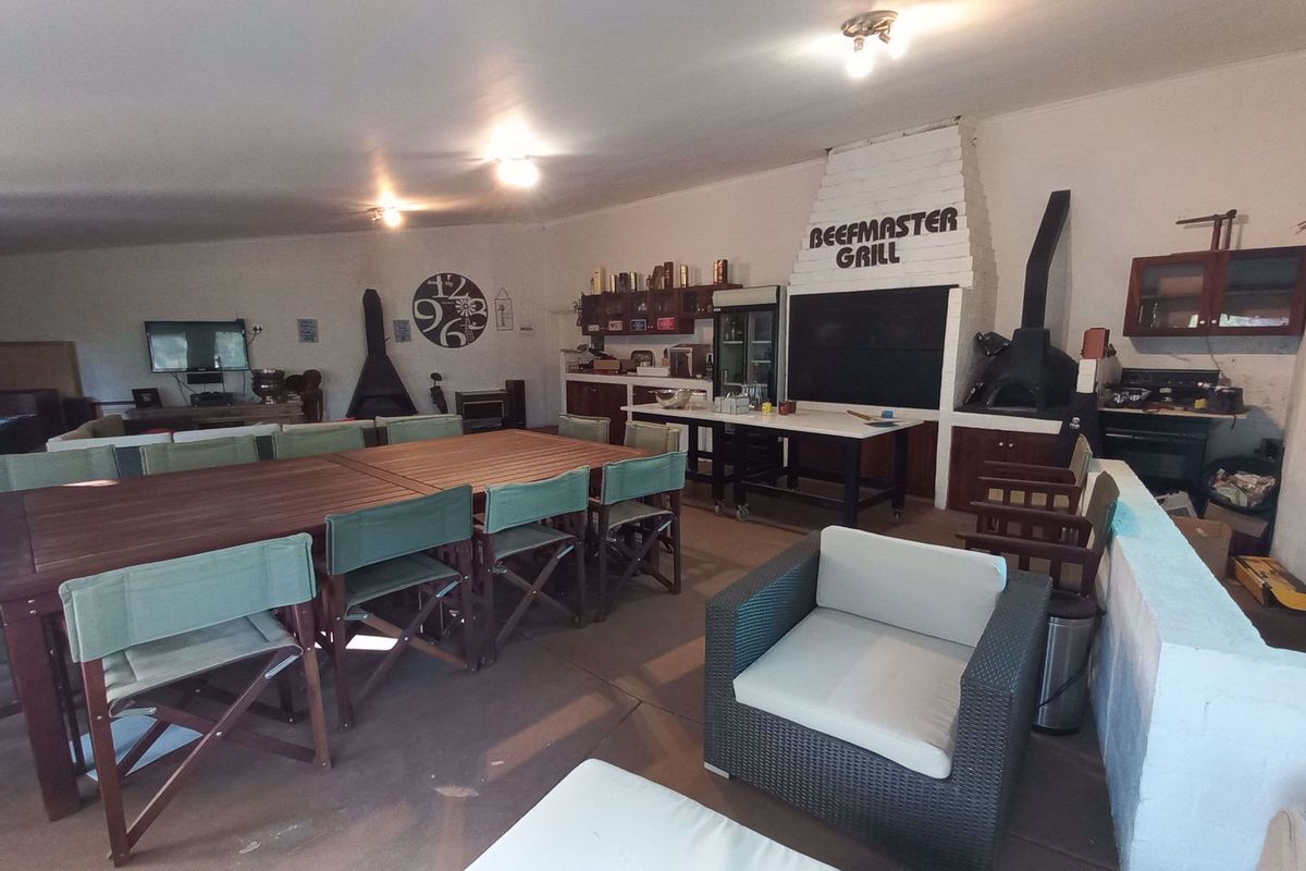 Spacious entertainment area featuring a built-in braai, brick fireplace, and ample room for dining and social gatherings.