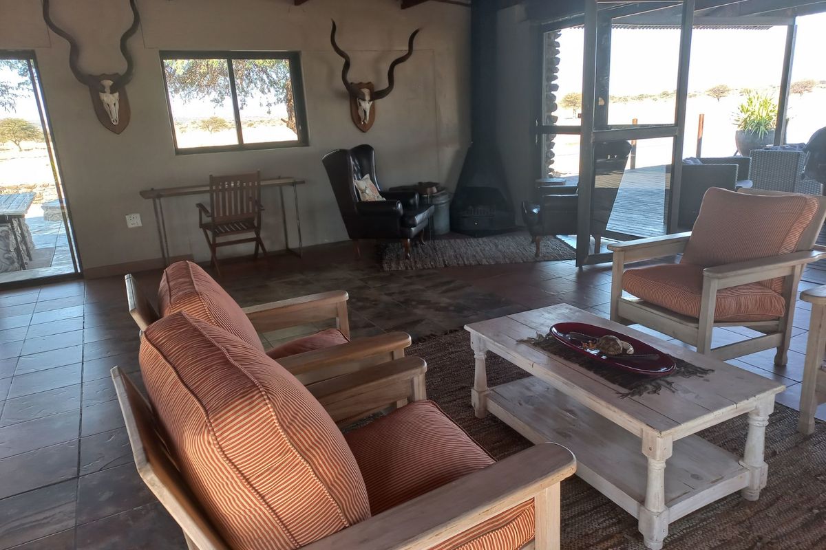 Spacious living area featuring exposed timber ceiling beams, tiled flooring, and a cozy freestanding fireplace with direct access to the outdoor patio.