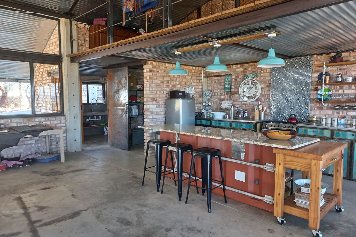 Industrial-style kitchen featuring exposed brick walls, corrugated metal ceiling, granite island, and a mezzanine level, offering a unique rustic aesthetic.