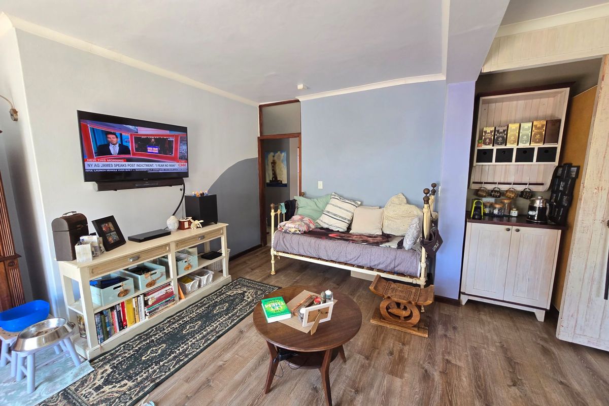 A living area featuring wood-look flooring, a built-in storage cabinet, and a wall-mounted television, creating a functional and cozy space.