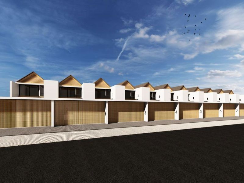 A modern townhouse development featuring a row of uniform units with timber-clad garage doors and distinctive pitched roof gables.