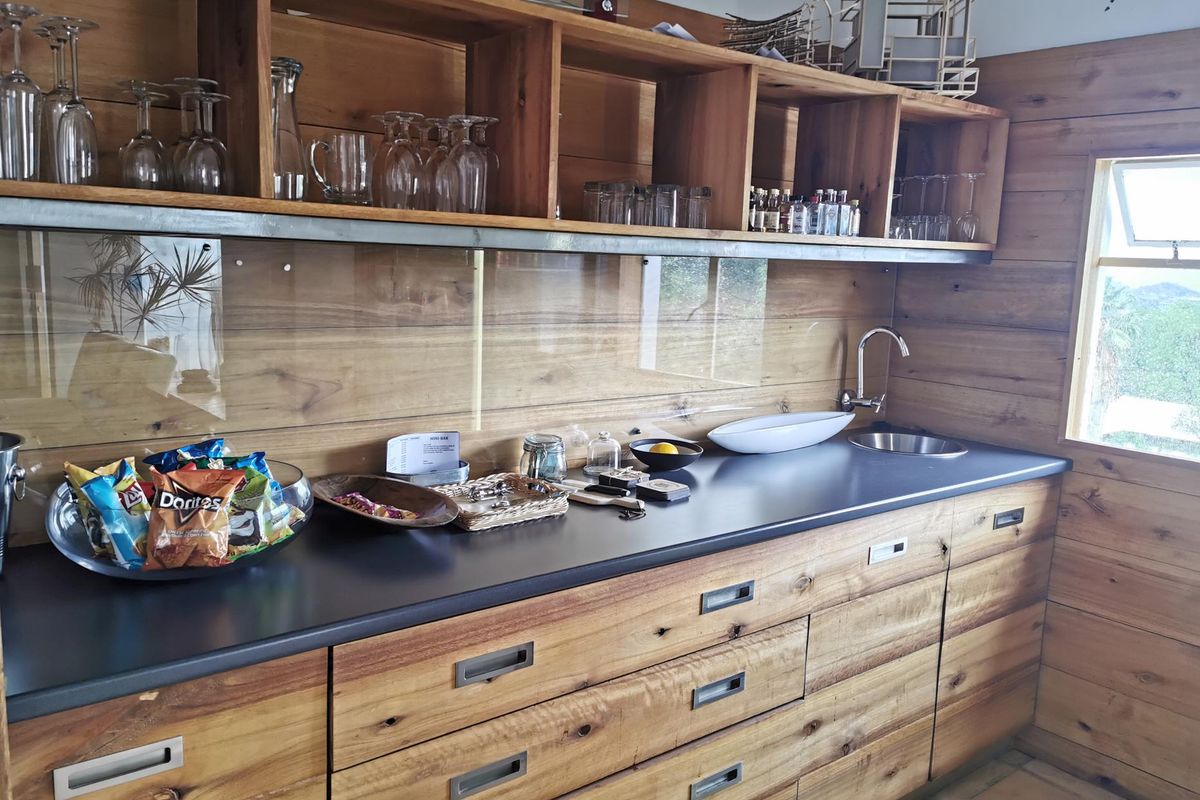 A well-appointed kitchenette featuring custom timber cabinetry, a sleek dark countertop, integrated sink, and open shelving for storage.
