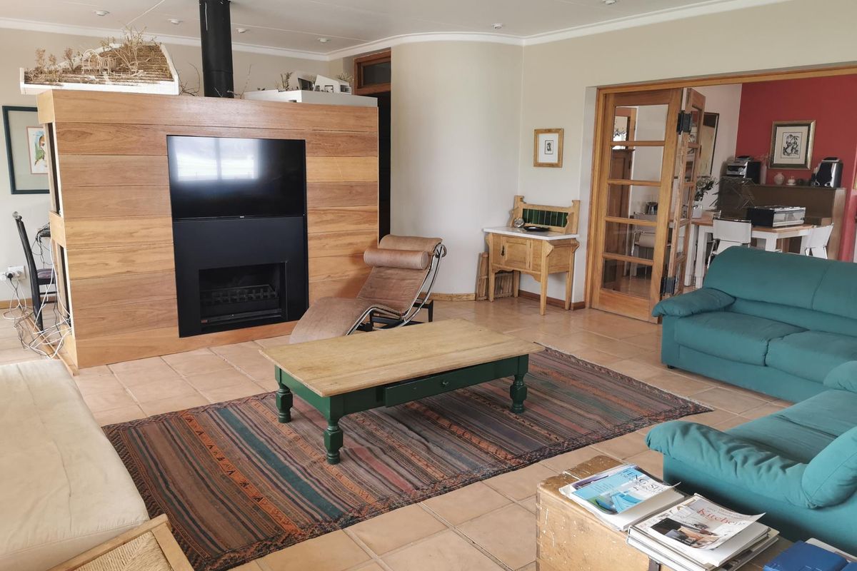 Spacious living area featuring a central timber-clad fireplace partition, tiled flooring, and French doors leading to an adjacent dining space.