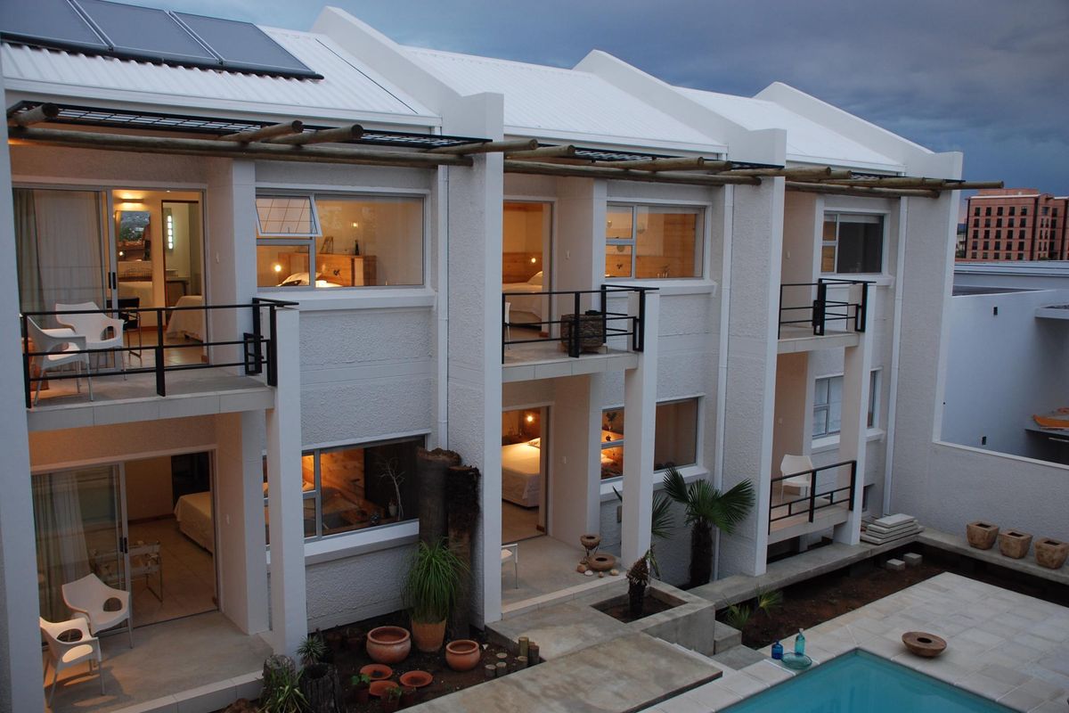Exterior view of a multi-level guest house featuring private balconies, modern architectural design, and a swimming pool area.