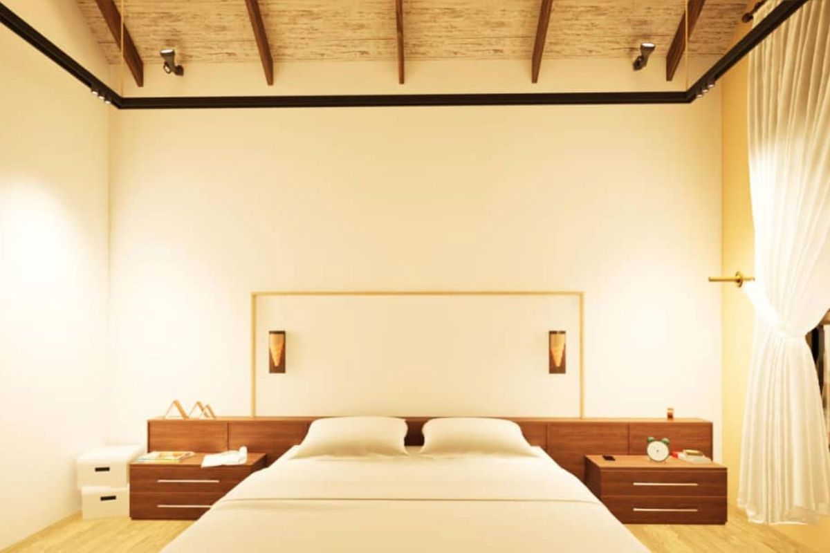 A modern bedroom featuring a vaulted timber-beamed ceiling, integrated wooden headboard with built-in bedside cabinetry, and warm ambient lighting.