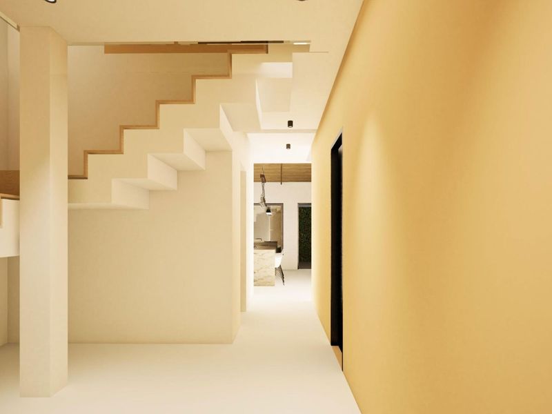 A modern, minimalist hallway featuring a clean staircase design and warm lighting, leading towards an open-plan living area.