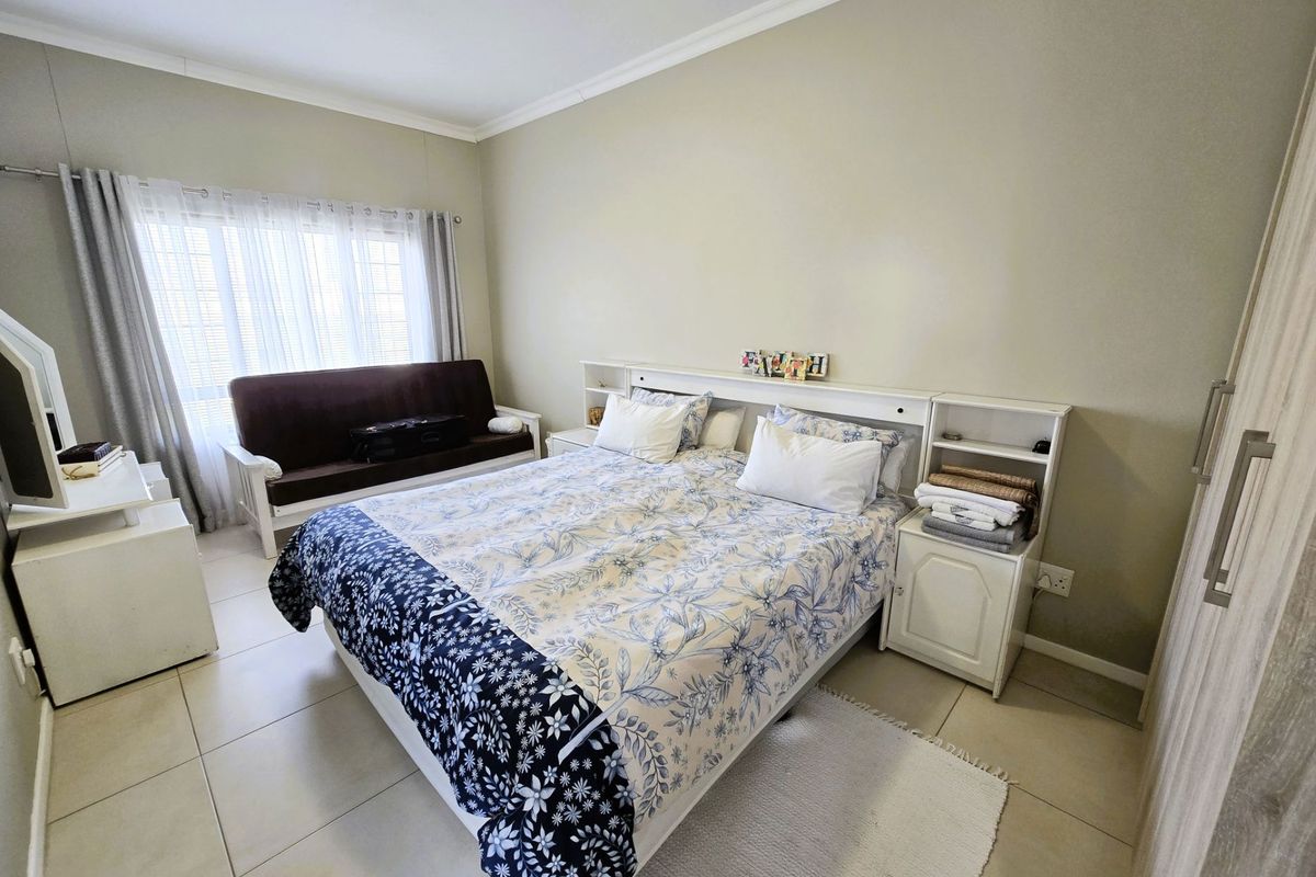 A well-maintained bedroom featuring neutral wall tones, tiled flooring, and built-in cabinetry with integrated bedside storage.