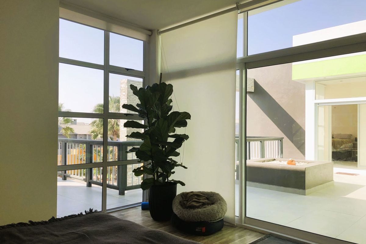 Bright bedroom featuring floor-to-ceiling windows with direct access to a spacious outdoor balcony area.