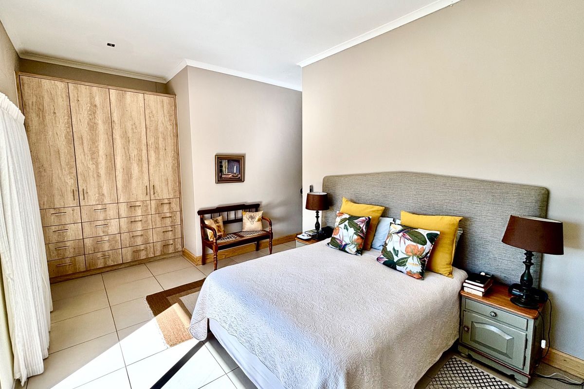 A well-maintained bedroom featuring built-in wooden cabinetry, tiled flooring, and neutral wall finishes, providing a clean and functional living space.