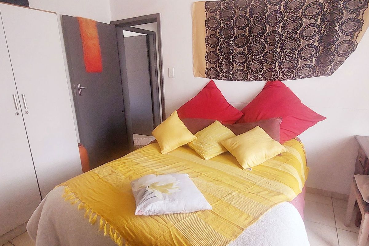 A functional bedroom featuring built-in wardrobe cabinetry and tiled flooring, providing a practical living space.