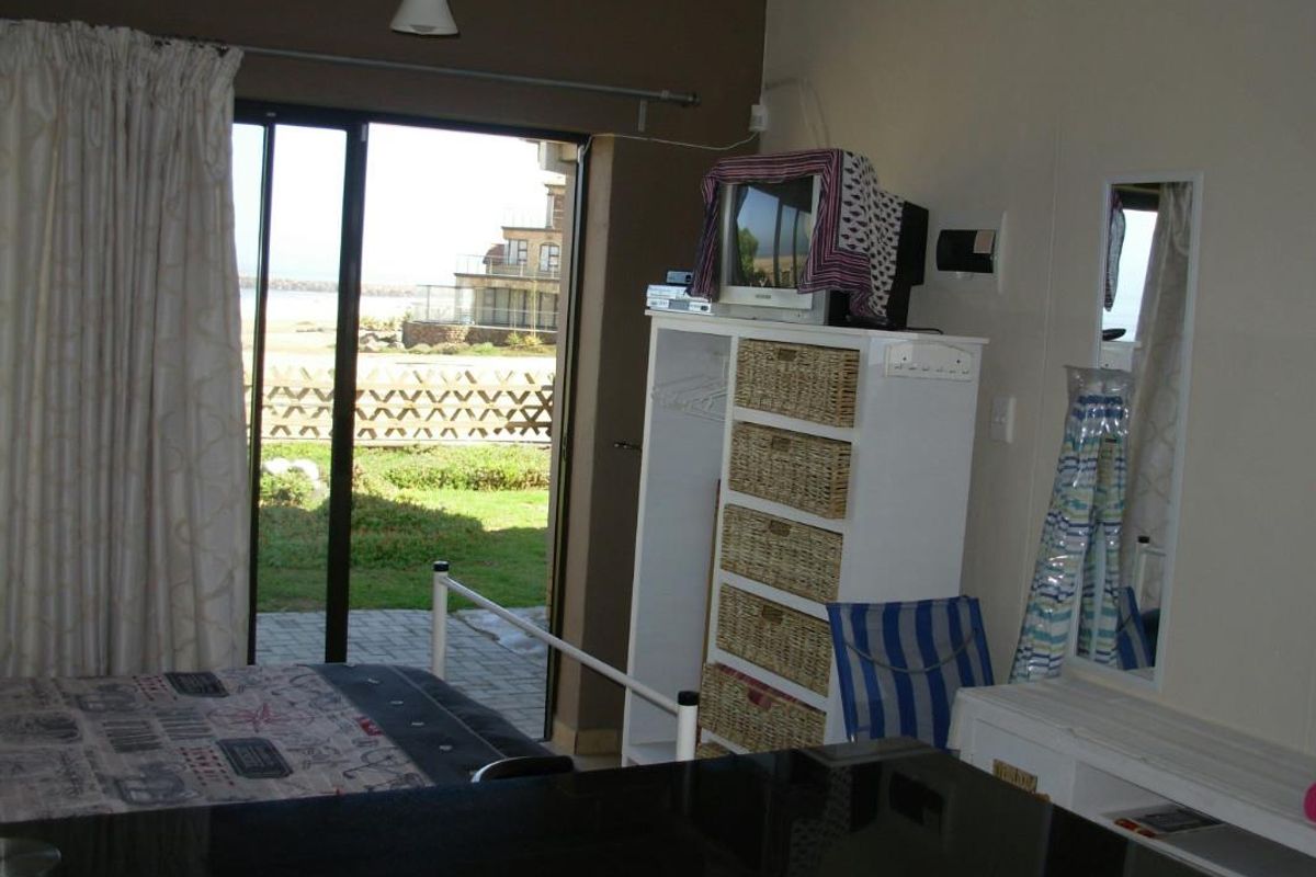 A bedroom featuring sliding glass doors that open to an outdoor patio area with coastal views.