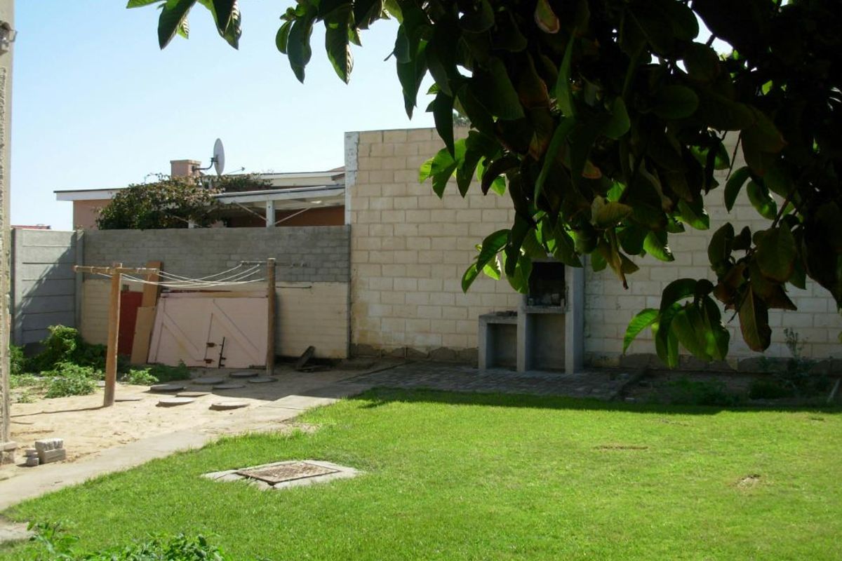 A rear garden area featuring a built-in brick braai, lawn space, and perimeter boundary walls.