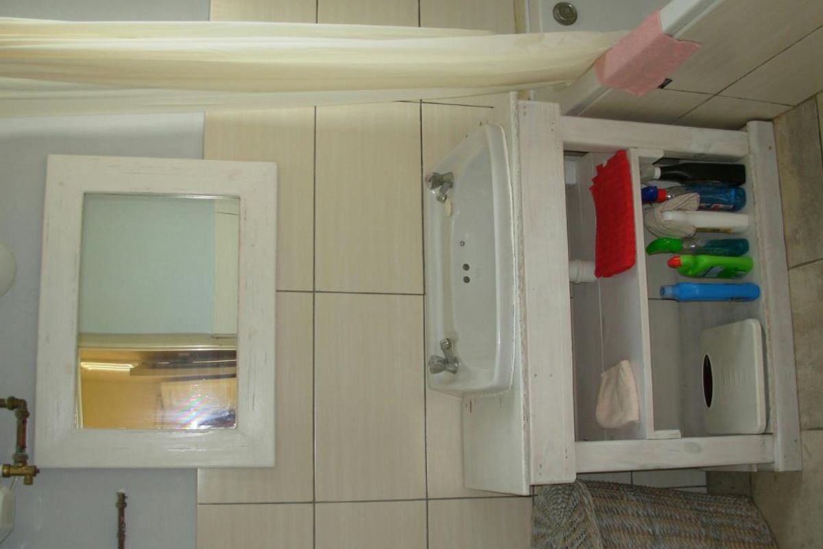 A functional bathroom featuring a wall-mounted basin, a custom-built vanity unit, and tiled wall finishes.