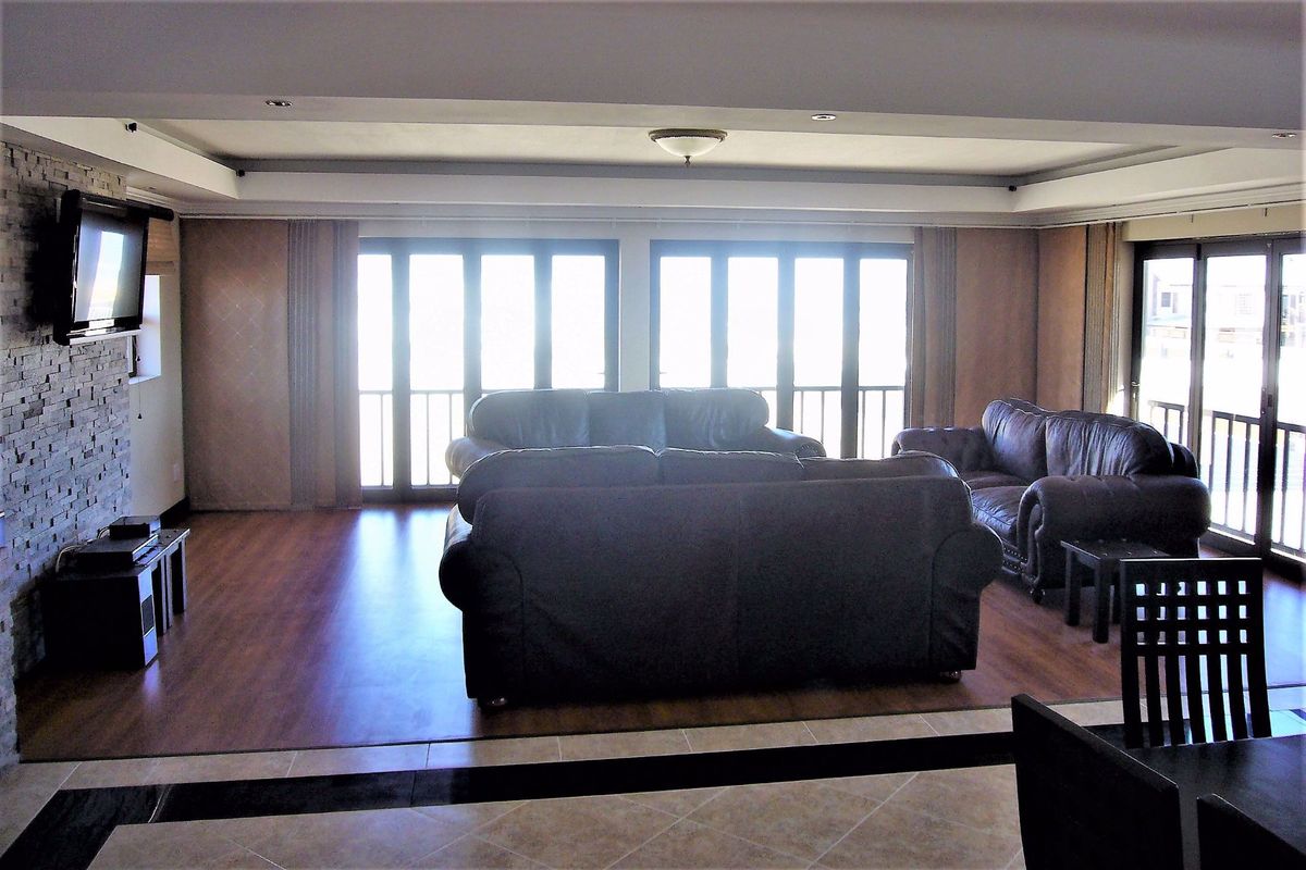 Spacious living area featuring wood-look flooring, a stone-clad feature wall, and large glass sliding doors providing ample natural light and access to the outdoors.